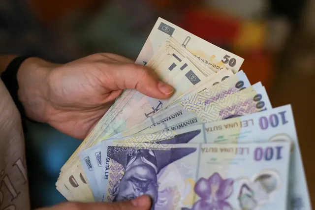 Mână care numără bancnote românești de 50 și 100 de lei
