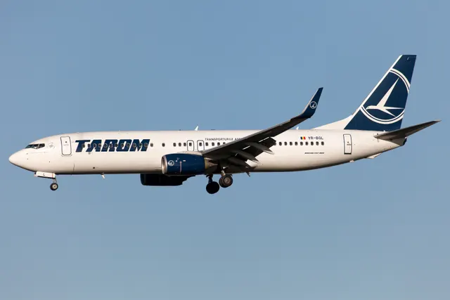 Avion TAROM în zbor, cu trenul de aterizare coborât, pe cer senin