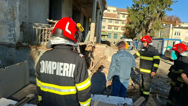 Pompieri la locul unde s-a prăbușit un zid, printre moloz, lângă o clădire veche