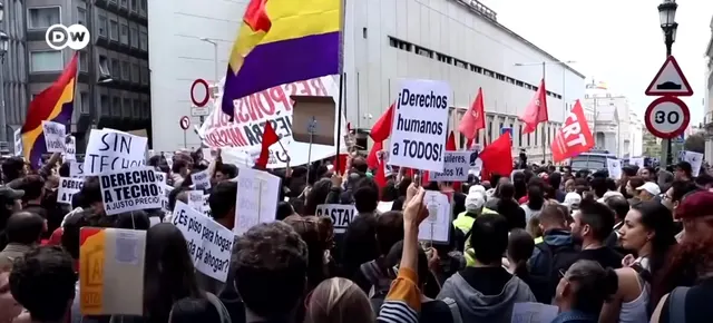 Protest pe o stradă din Spania, cu pancarte pentru dreptul la locuință și steaguri republicane