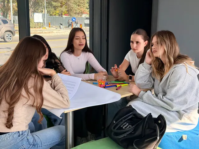 Patru eleve la o masă, ascultând și luând notițe în timpul unui atelier