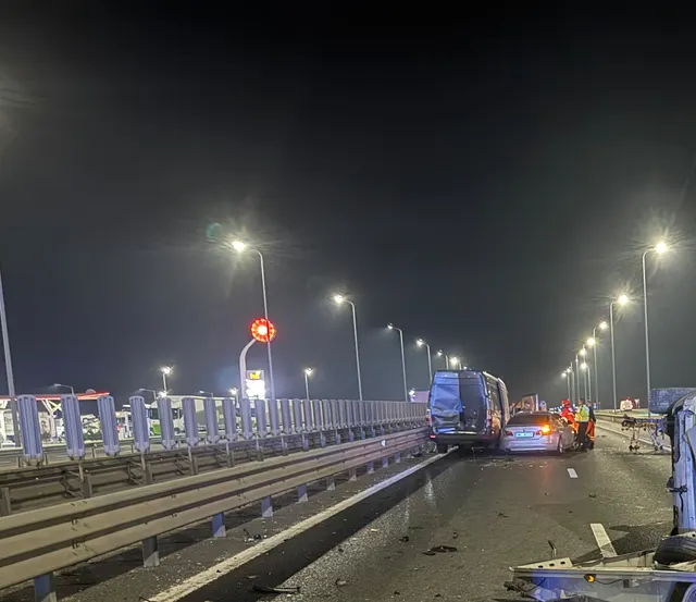 Autostradă noaptea, sub stâlpi de iluminat, cu vehicule oprite și resturi pe carosabil după un accident