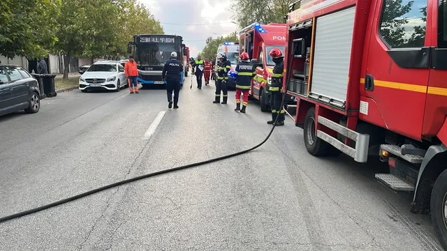 Autospeciale de pompieri și salvatori pe o stradă, cu un furtun întins pe asfalt și un autobuz oprit în față